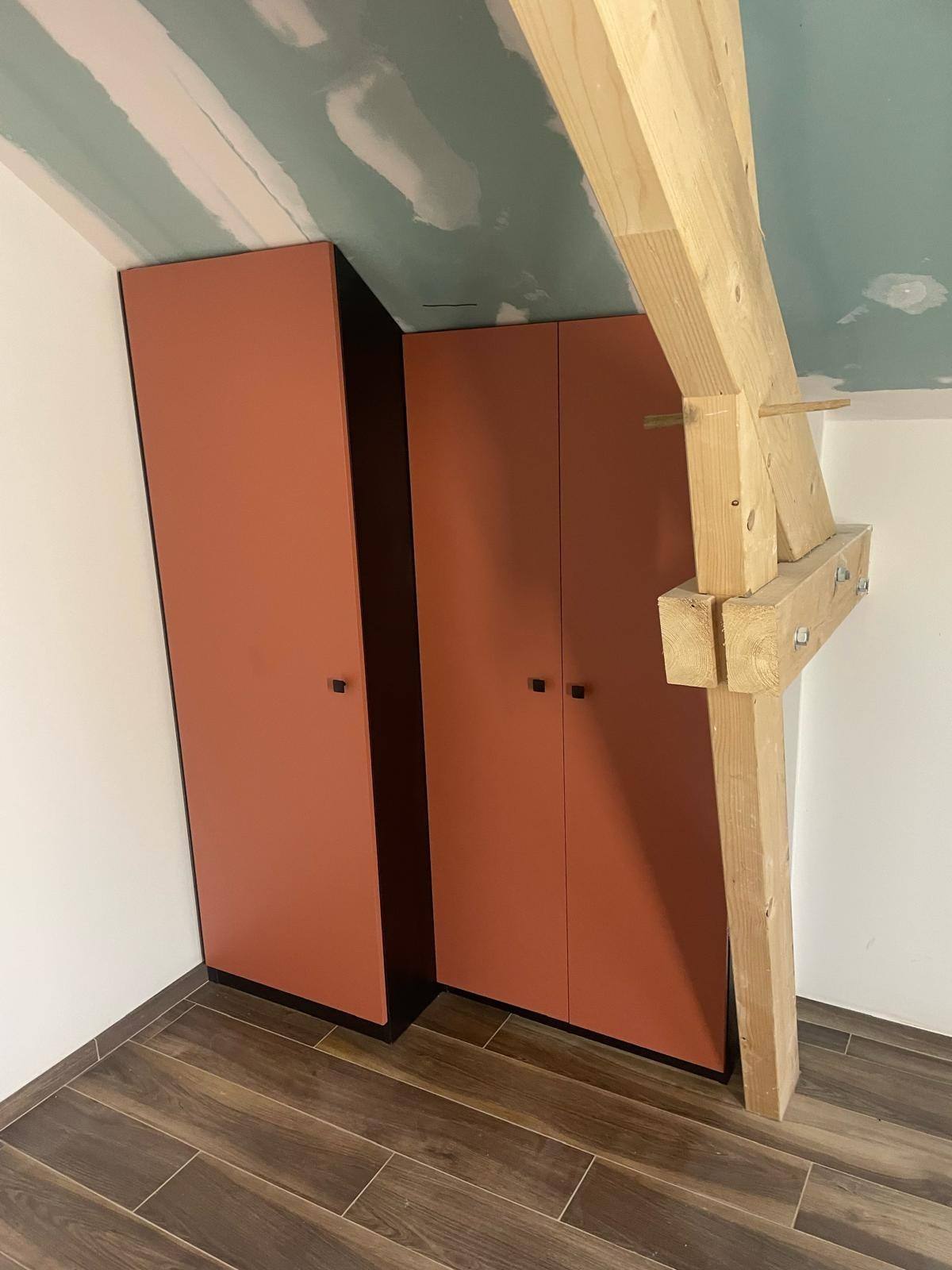 Armoire terracotta sur mesure ajustée contre une poutre de charpente, à Marne-la-Vallée