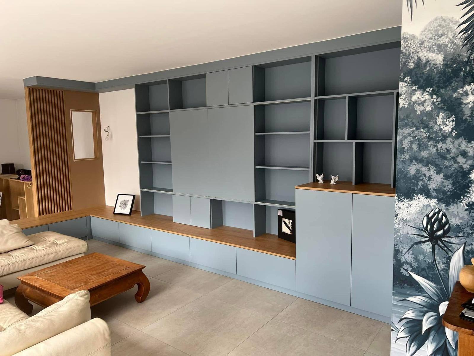 Bibliothèque murale bleu gris avec meuble TV et banquette bois, dans un salon à Paris 17e