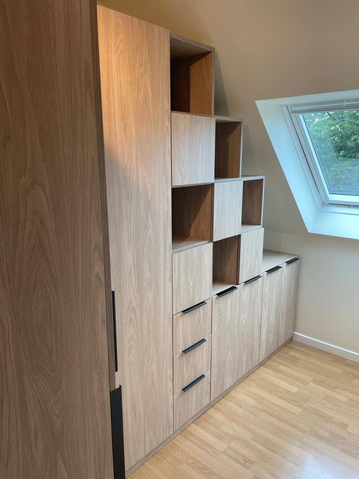Meuble sous pente en bois clair avec niches en escalier et tiroirs, à Pierrelaye