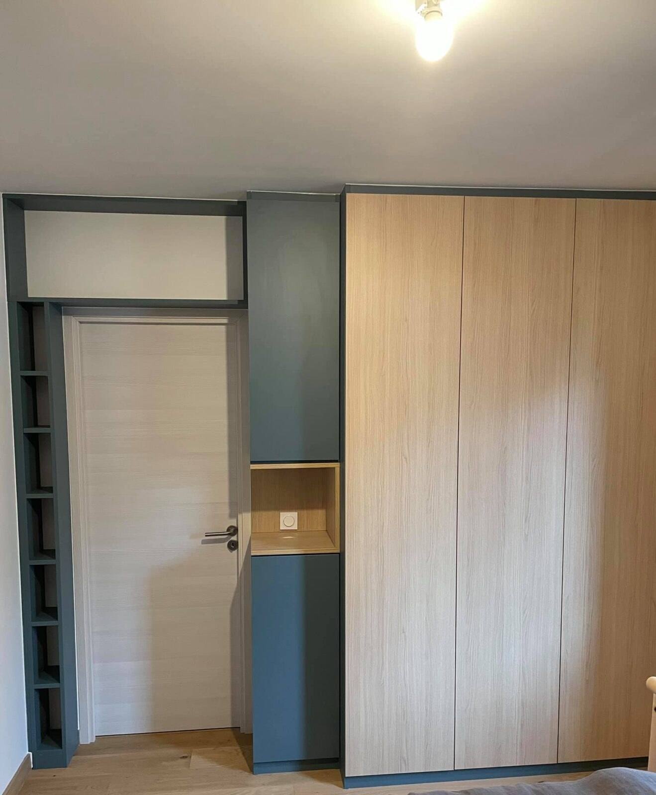 Placard en chêne et bleu canard encadrant une porte, avec étagères latérales