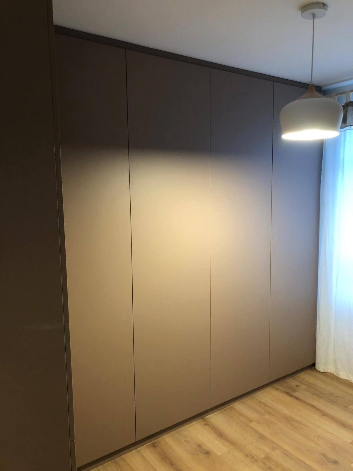 Placard toute hauteur taupe mat sans poignées dans une chambre